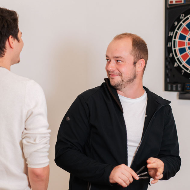 Zwei Mitarbeiter fröhlich beim Dartspiel